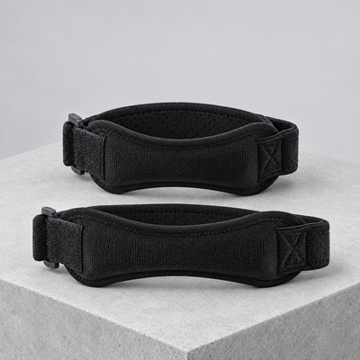 Two black patella knee straps on a concrete block