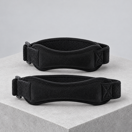 Two black patella knee straps on a concrete block