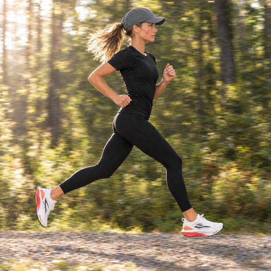 Woman running on a forest road in the grey running cap