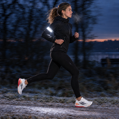Woman running before sunrise with the light band on her arm