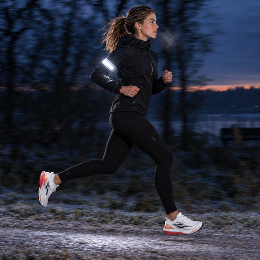 Woman running before sunrise with the light band on her arm